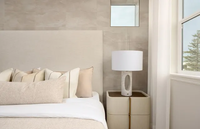 a white bed sitting in a bedroom next to a window