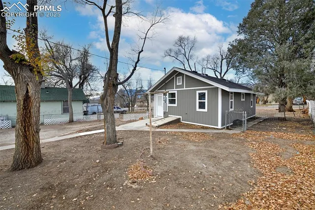 a view of a house with a yard and large tree
