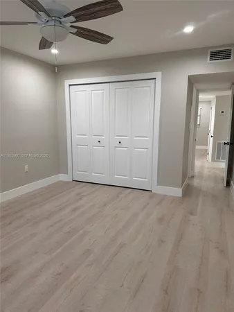 an empty room with wooden floor cabinet and windows
