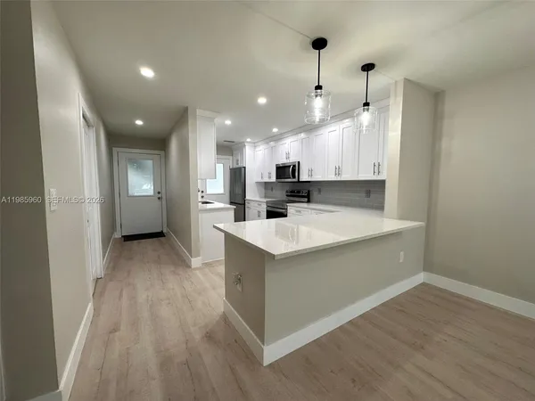 a large kitchen with a large counter top a sink stainless steel appliances and cabinets