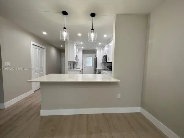 a large kitchen with granite countertop a large kitchen island and a wooden floor