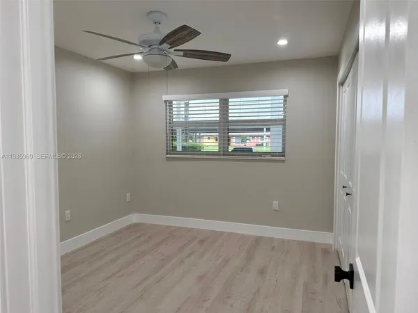 an empty room with wooden floor fan and windows