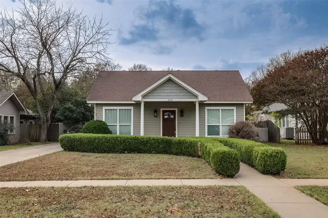 a view of a house with a yard plants and large tree