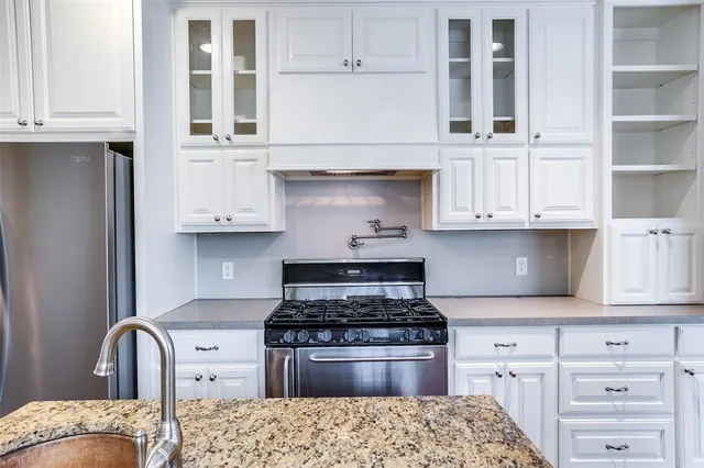 a kitchen with granite countertop white cabinets and stainless steel appliances