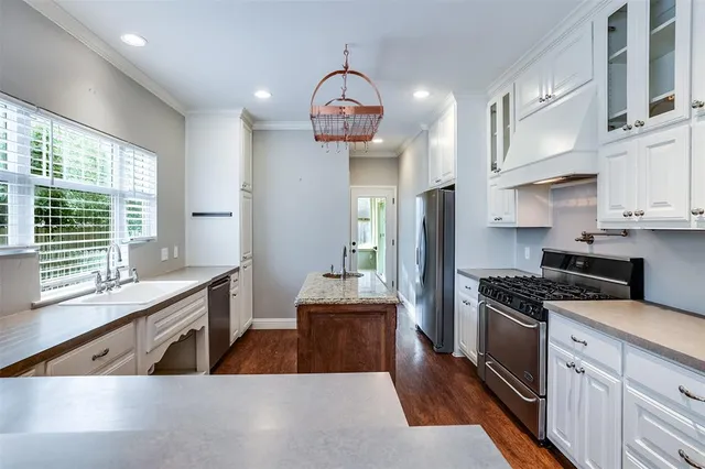 a kitchen with kitchen island granite countertop a stove a sink a refrigerator and a granite counter tops