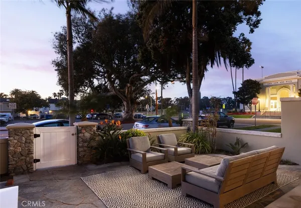 a view of a patio with couches and chairs under an umbrella with a fire pit