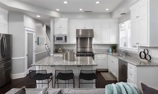 a kitchen with kitchen island granite countertop a sink refrigerator and cabinets