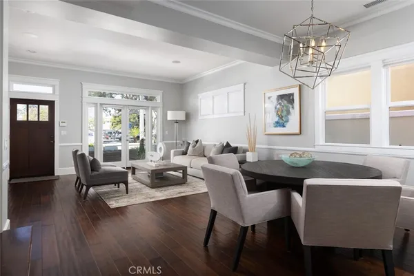 a dining room with wooden floor a chandelier a glass table and chairs