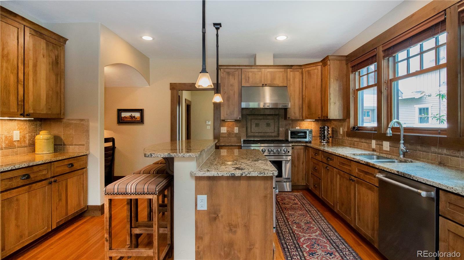 21 Meadow Trail Fraser, CO 80442 - Photo 18 of 36 a kitchen with stainless steel appliances granite countertop wooden cabinets a sink dishwasher a stove and a refrigerator with wooden floor