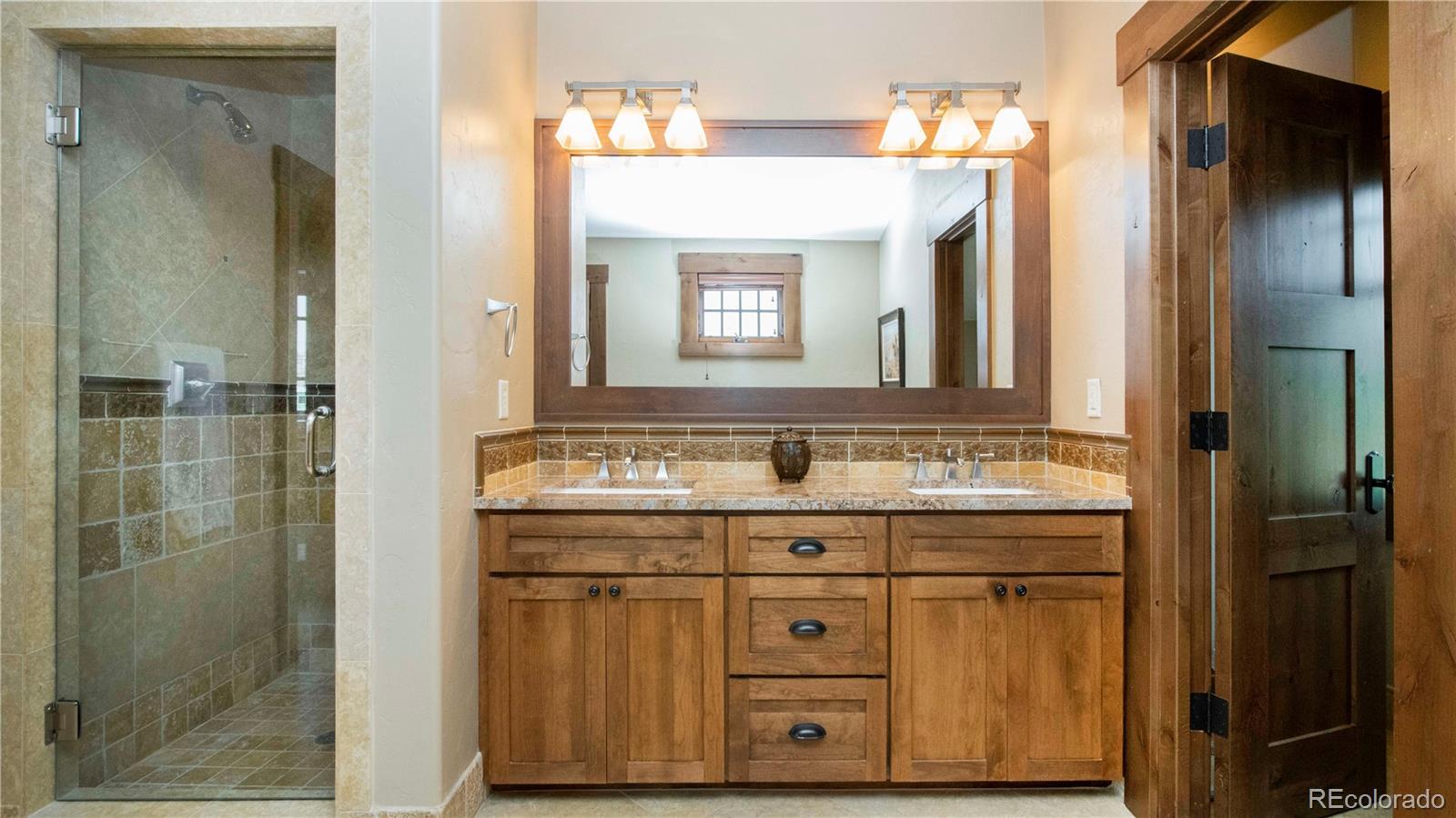 21 Meadow Trail Fraser, CO 80442 - Photo 29 of 36 a bathroom with a granite countertop sink a mirror and a shower