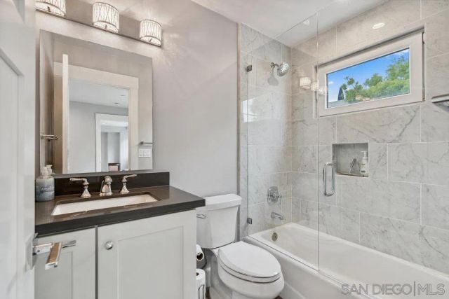 a bathroom with a bathtub shower sink vanity and toilet