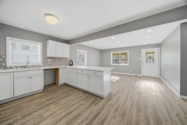 a kitchen with wooden floors and white cabinets