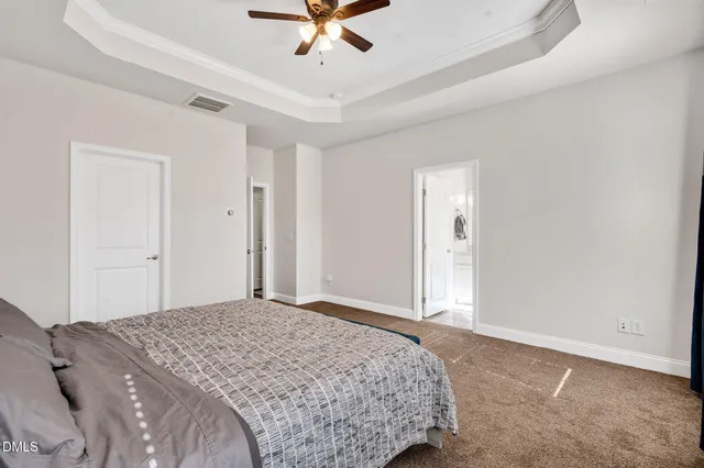 a bedroom with a large bed and a chandelier fan