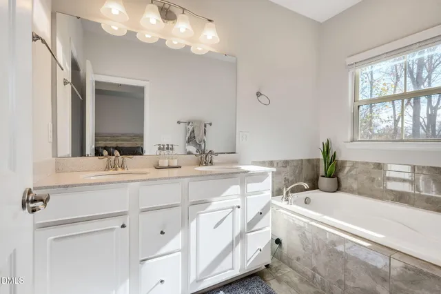 a bathroom with a granite countertop double vanity sink a mirror and a bathtub