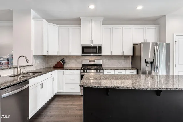 a kitchen with granite countertop white cabinets and stainless steel appliances