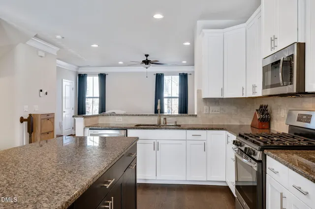 a kitchen with stainless steel appliances granite countertop a sink stove and cabinets