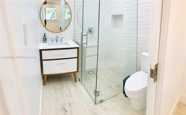a bathroom with a toilet sink vanity granite and a mirror