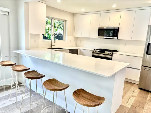a kitchen with stainless steel appliances a stove a sink a table and chairs