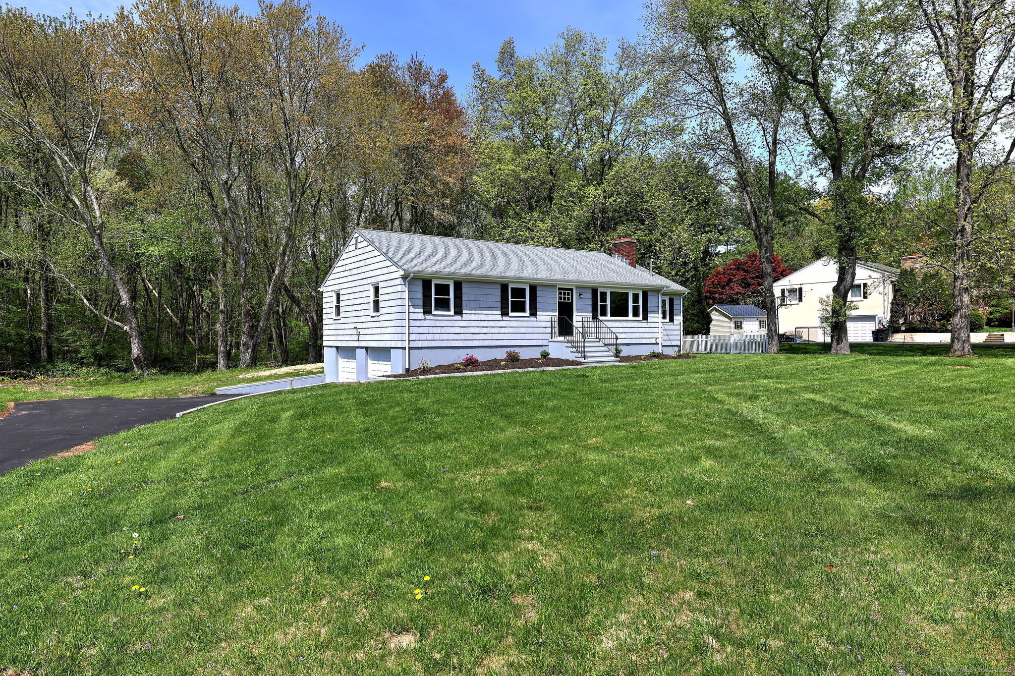 a front view of a house with a garden and trees