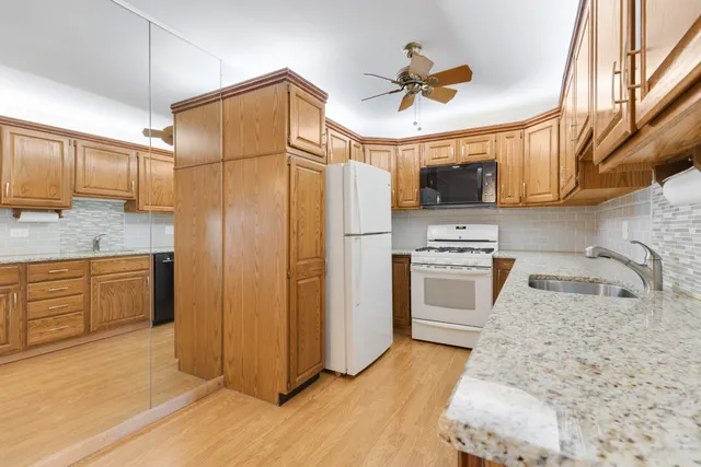a kitchen with stainless steel appliances granite countertop a refrigerator a stove and a sink with wooden floor