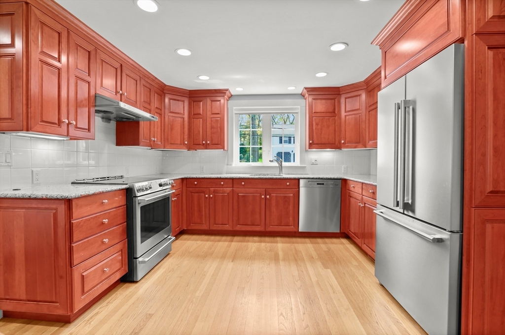 109 Suffolk Road Wellesley, MA 02481 - Photo 4 of 24 a kitchen with stainless steel appliances granite countertop a refrigerator a sink dishwasher a stove with wooden cabinets and floor