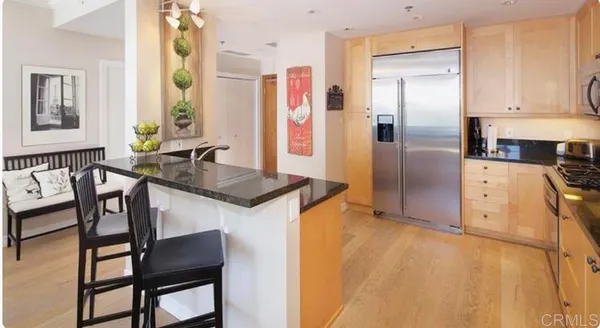 a kitchen with stainless steel appliances granite countertop a table chairs and a refrigerator