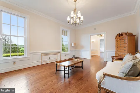 a view of a room with wooden floor chandelier and fireplace