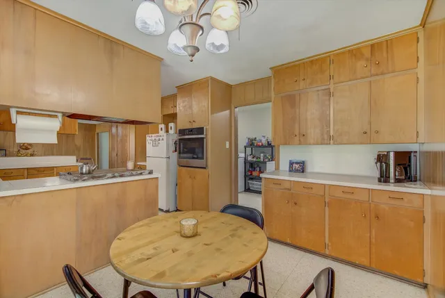 a kitchen with stainless steel appliances granite countertop a sink dishwasher a stove a refrigerator with a dining table and chairs