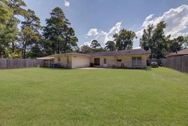 a front view of house with yard and trees in the background
