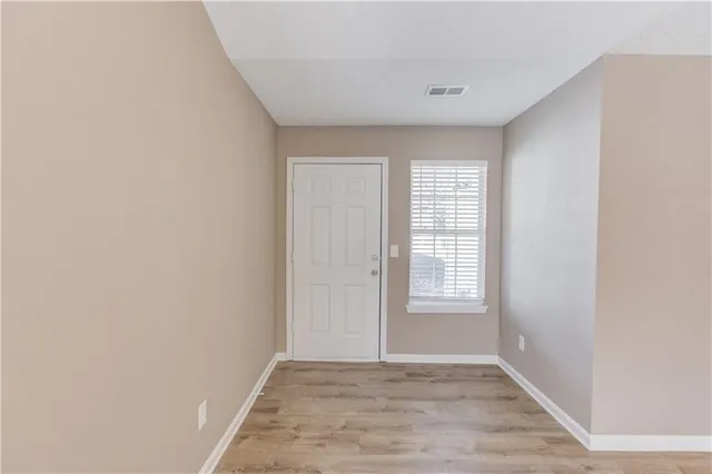 a view of an empty room with window and wooden floor