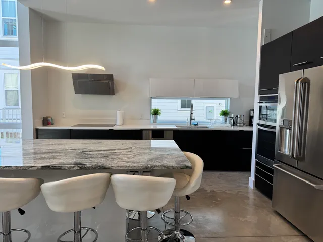 a kitchen with stainless steel appliances granite countertop a sink a stove a refrigerator a dining table and chairs