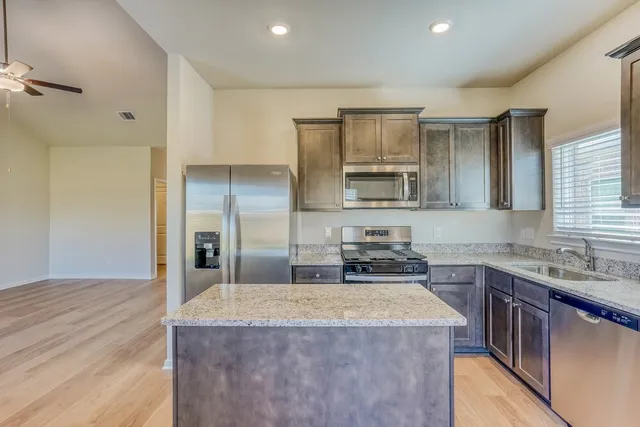 a kitchen with a stove a sink a refrigerator and cabinets