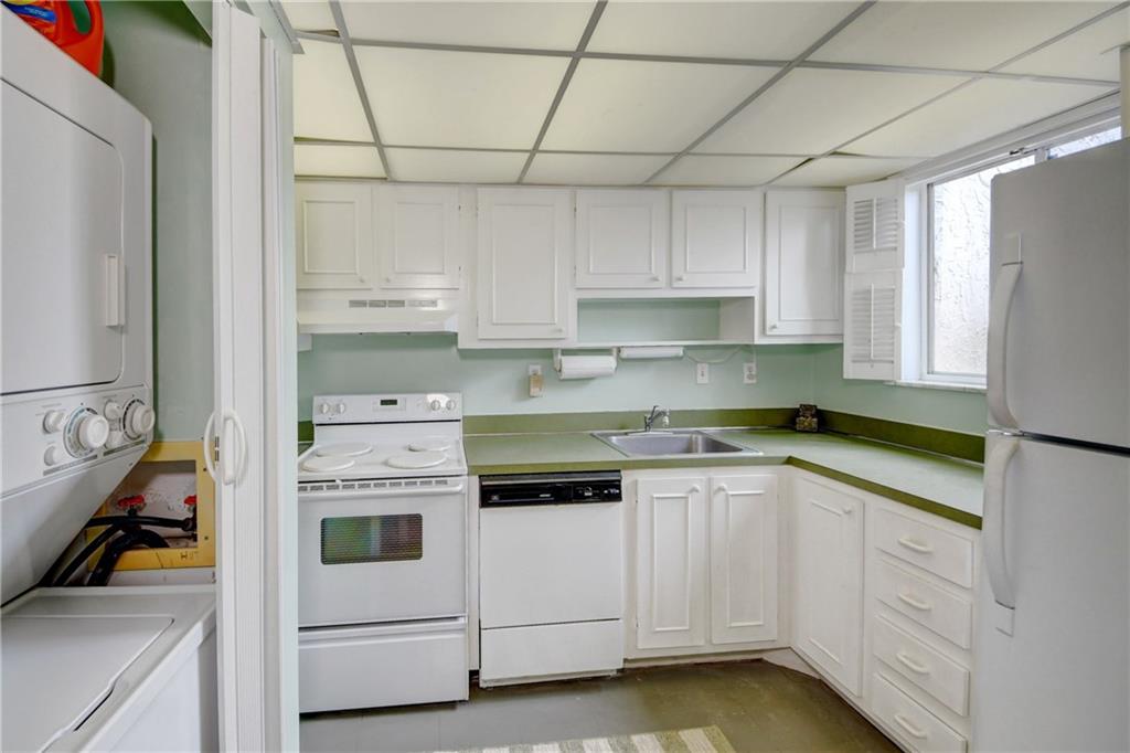 5111 Southeast Miles Grant Road, Unit 104 Stuart, FL 34997 - Photo 12 of 36 a kitchen with white cabinets and white appliances