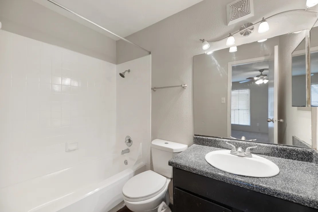 2800 South Ashford Road, Unit 2206 Houston, TX 77082 - Photo 20 of 35 a bathroom with a granite countertop sink a toilet a mirror and shower