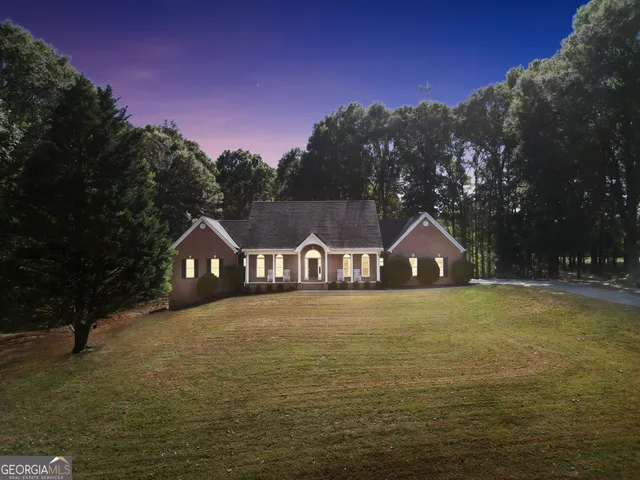 a front view of a house with a yard and a large tree