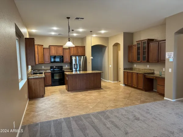 a large kitchen with stainless steel appliances granite countertop a stove top oven a sink and a refrigerator