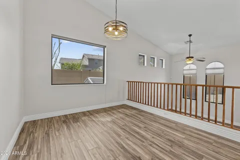 a view of empty room with wooden floor and fan