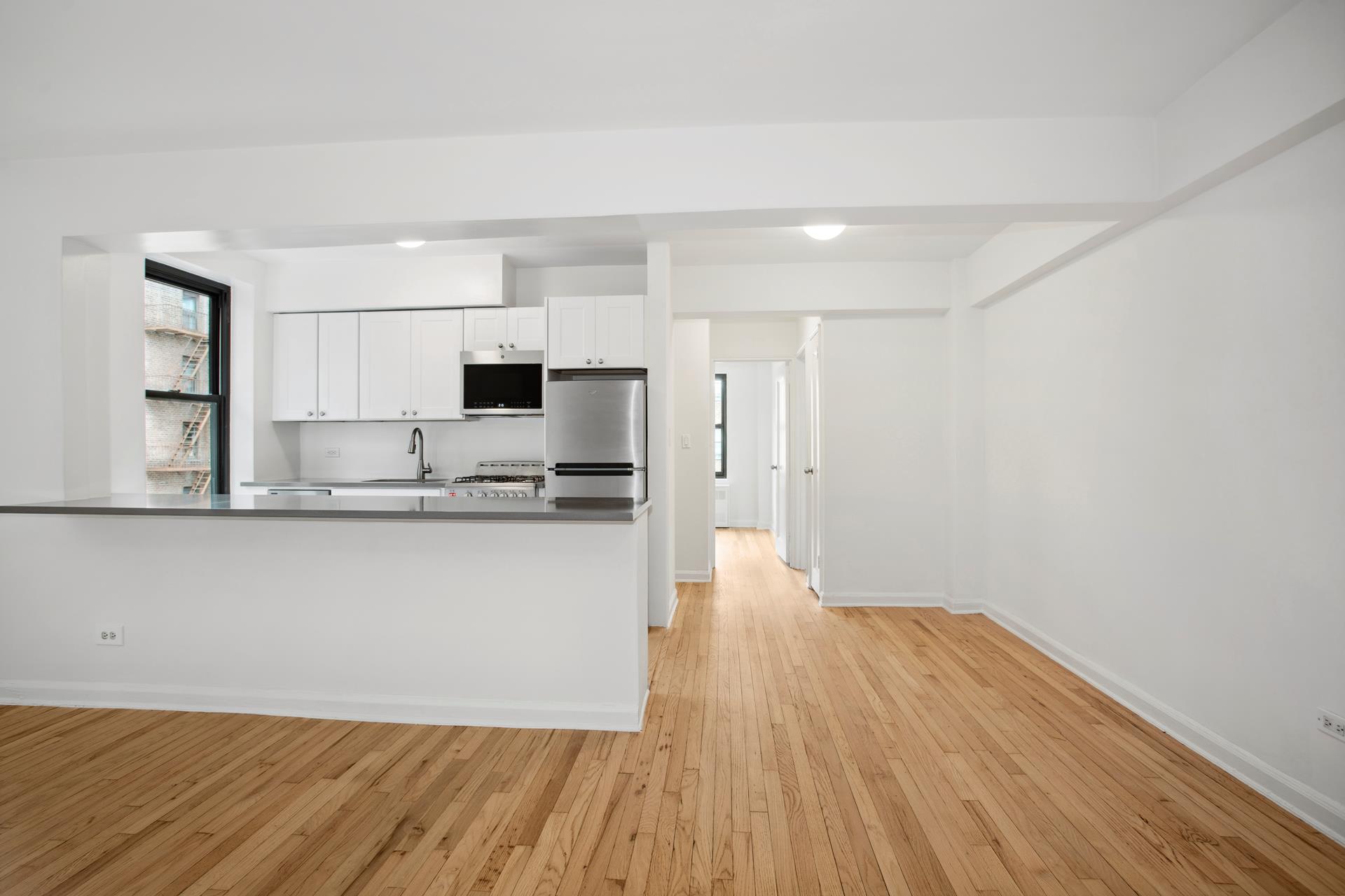 4489 Broadway, Unit 5E Manhattan, NY 10040 - Photo 3 of 13 a view of kitchen with stainless steel appliances wooden floor and window