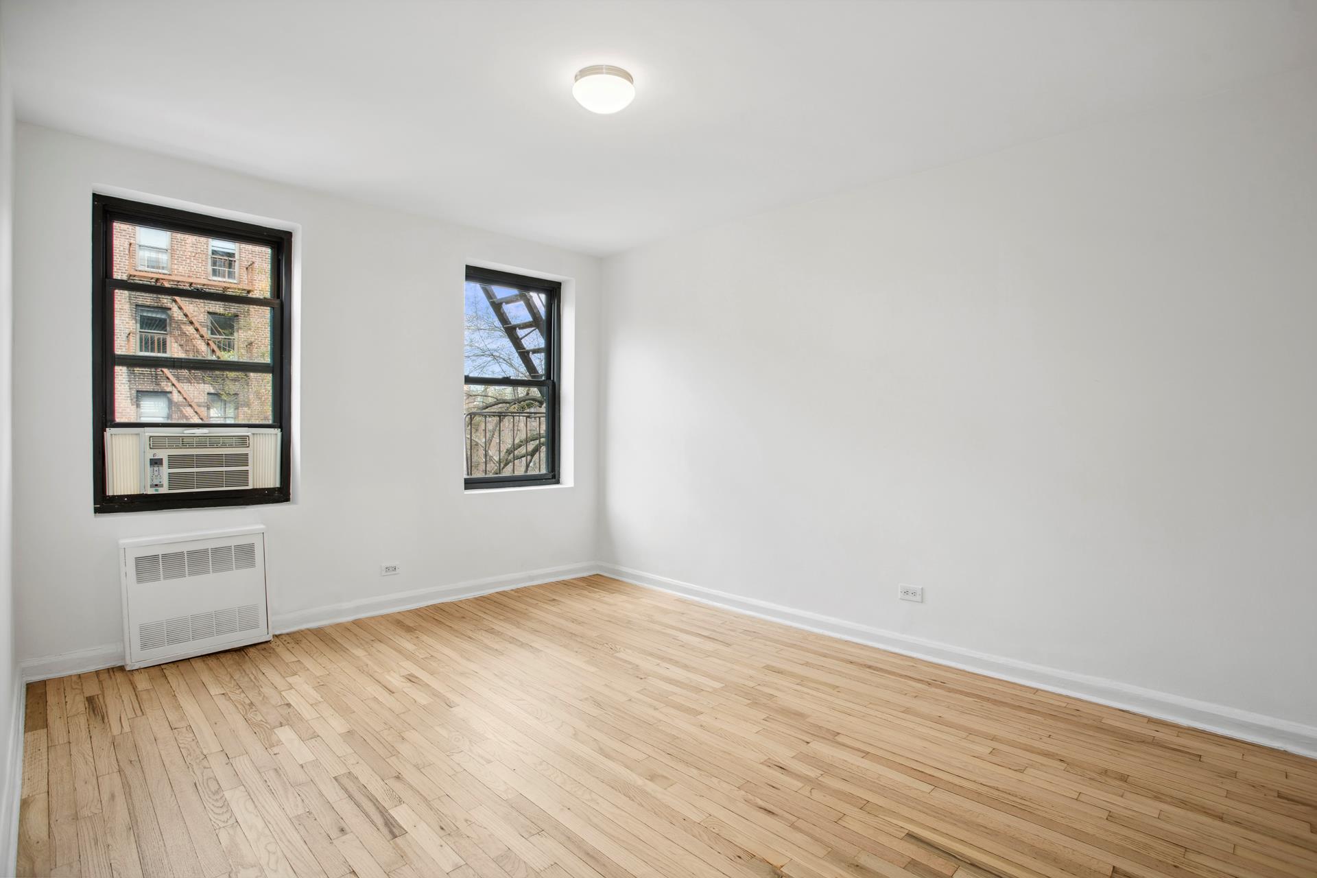 4489 Broadway, Unit 5E Manhattan, NY 10040 - Photo 5 of 13 an empty room with wooden floor and windows