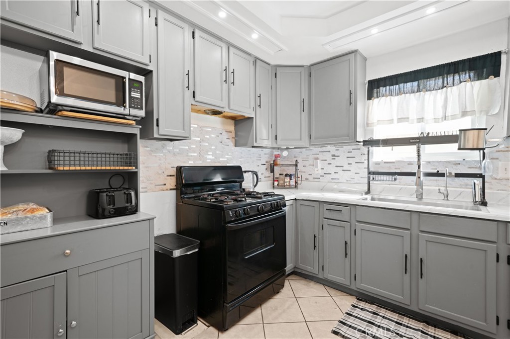 18859 6th Street Bloomington, CA 92316 - Photo 9 of 31 a kitchen with stainless steel appliances granite countertop white cabinets a sink a stove a window and white cabinets
