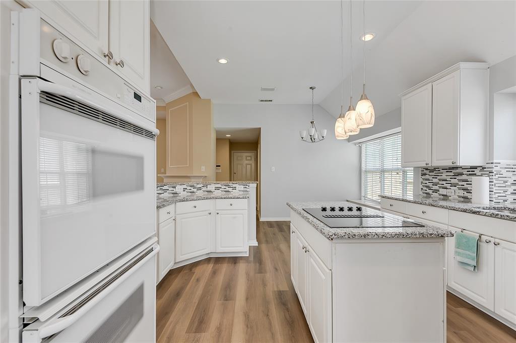 1404 Ranch Hill Drive Irving, TX 75063 - Photo 13 of 31 Kitchen featuring white cabinetry, light granite-style countertops, wood-finish flooring, a built-in wall oven, and a kitchen island with an integrated cooktop