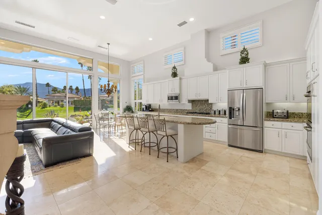 a kitchen with granite countertop a refrigerator and white cabinets