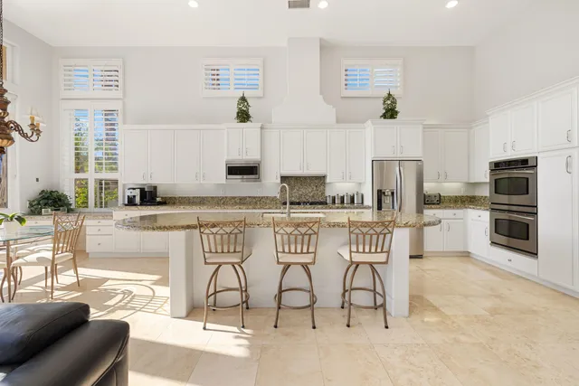 a view of kitchen with stainless steel appliances kitchen island granite countertop a stove a sink a dining table and chairs