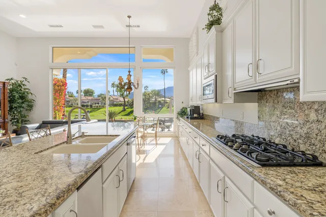 a kitchen with stainless steel appliances granite countertop a sink a stove and a wooden floors