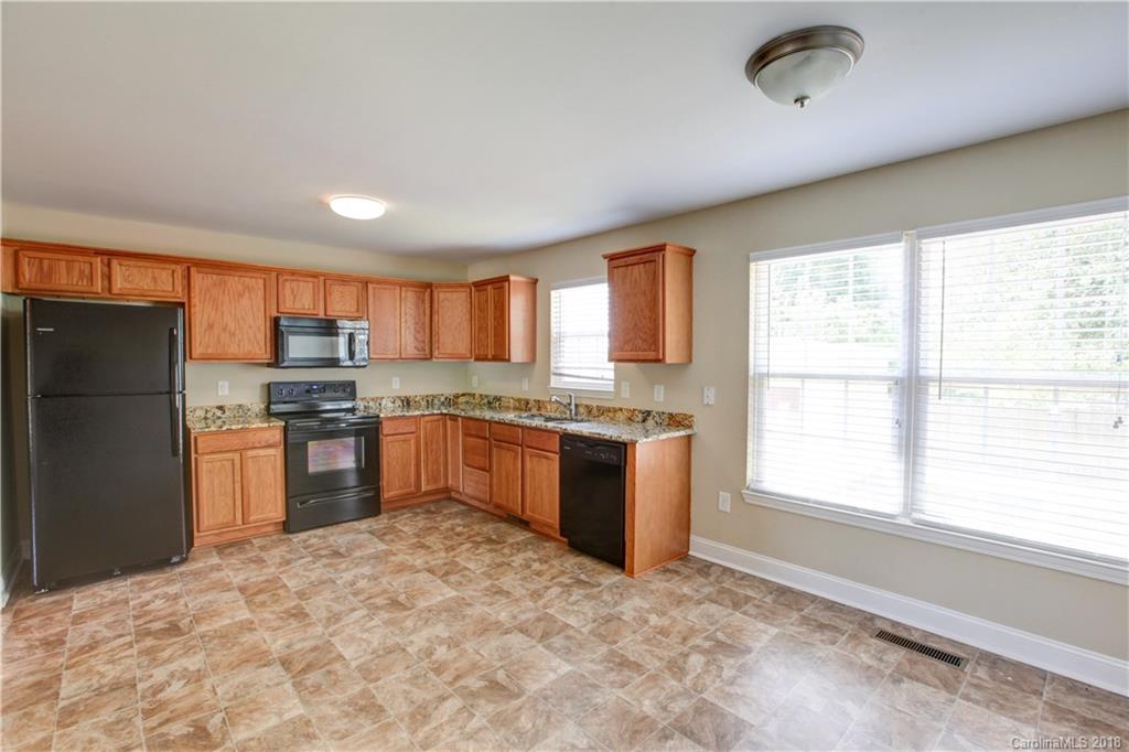 3713 Austin Road Monroe, NC 28112 - Photo 11 of 19 a kitchen with granite countertop a refrigerator and a stove top oven