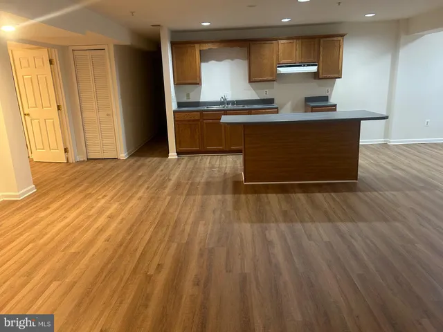 a large kitchen with stainless steel appliances a large counter top a stove and a wooden floors