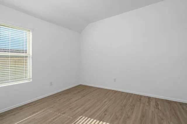 a view of a room that has wooden floor and window