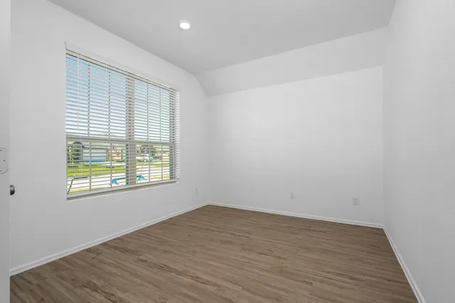 an empty room with wooden floor and windows
