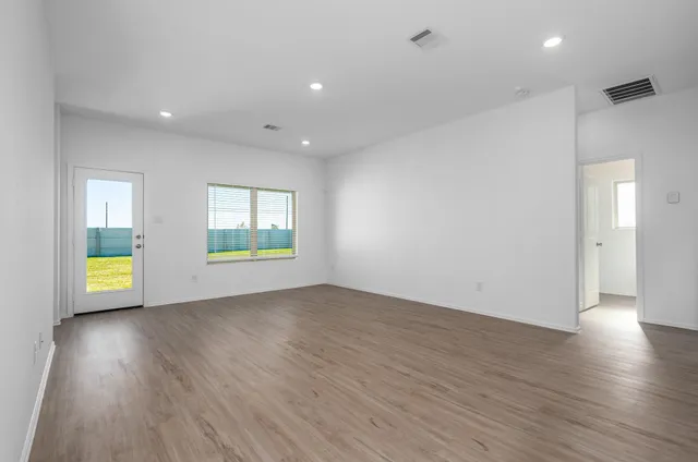 an empty room with wooden floor and windows