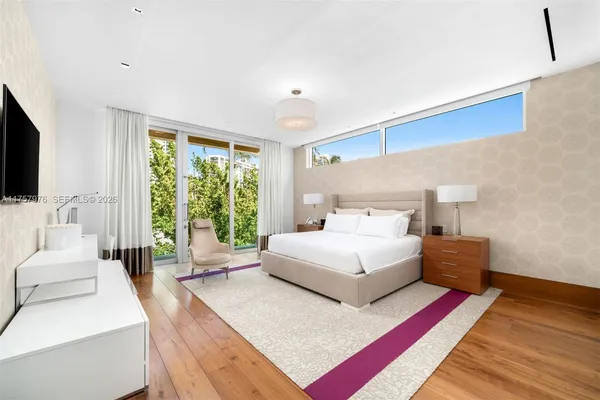a spacious bedroom with a bed and a flat screen tv